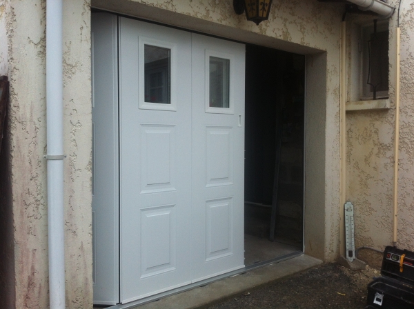 Porte de garage coulissante laterale, avec hublots.